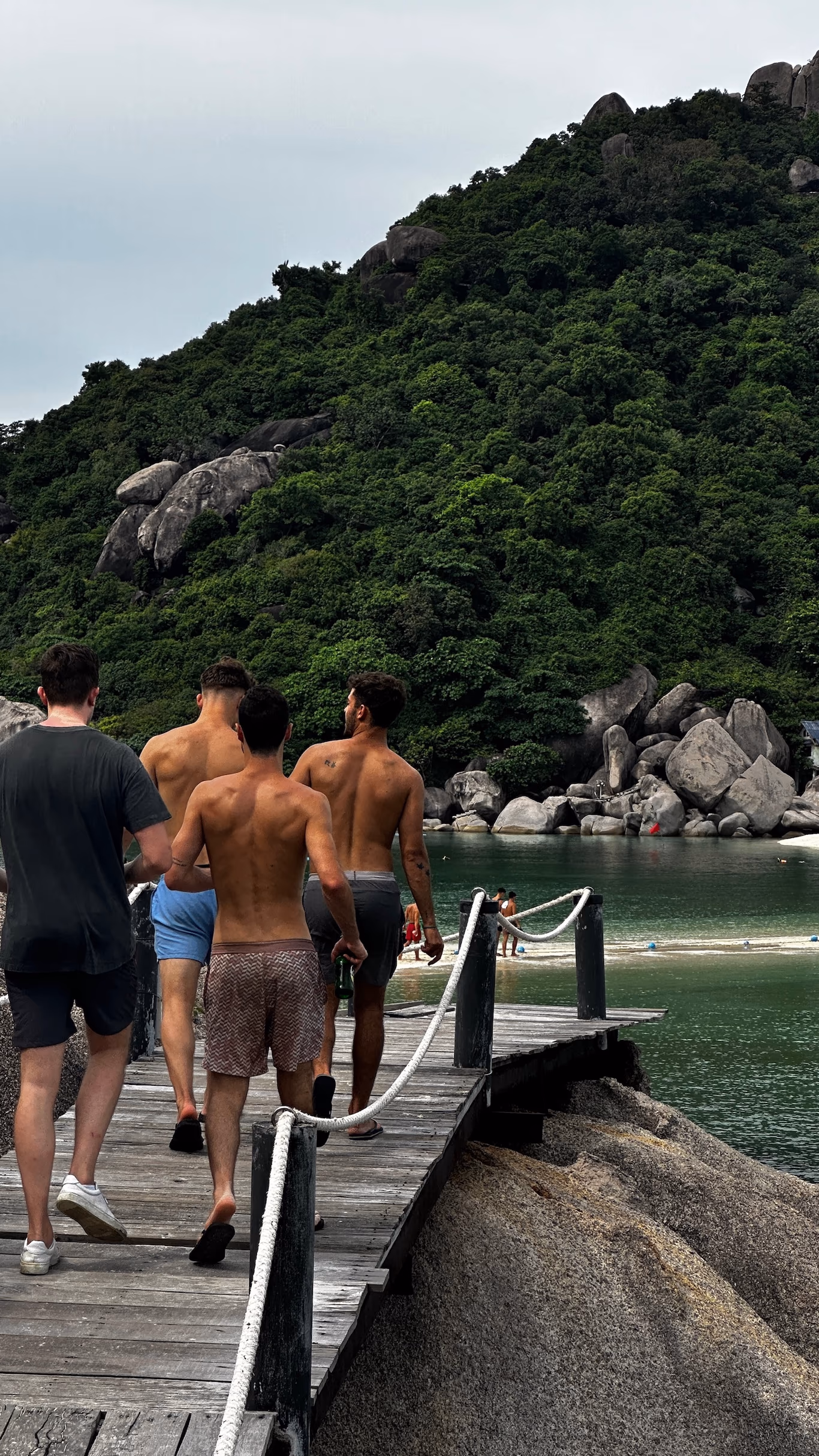 Four founders walking down a wooden dock toward the bay on a Helix trip, forested hillside behind